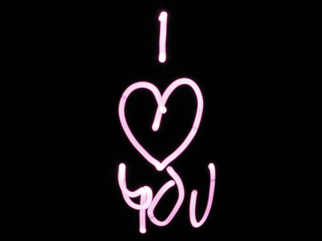 Bright pink light painting of 'I Love You' on a black background, perfect for Valentine's Day.