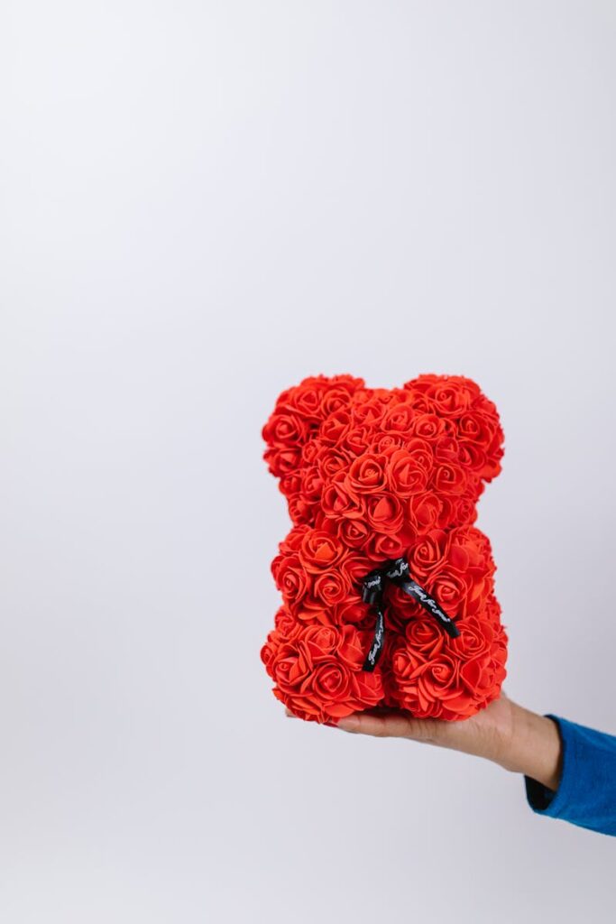 A unique red rose teddy bear held in hand, perfect for Valentine's Day gifts.